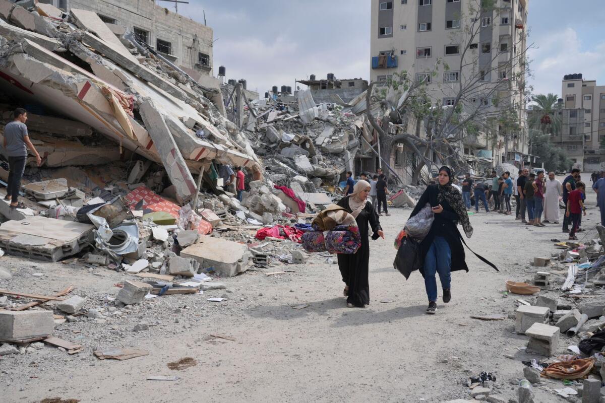 Palestinian women walk by buildings destroyed in Israeli airstrikes in Nuseirat camp in the central Gaza Strip, Monday, Oct. 16, 2023. Photo: AP