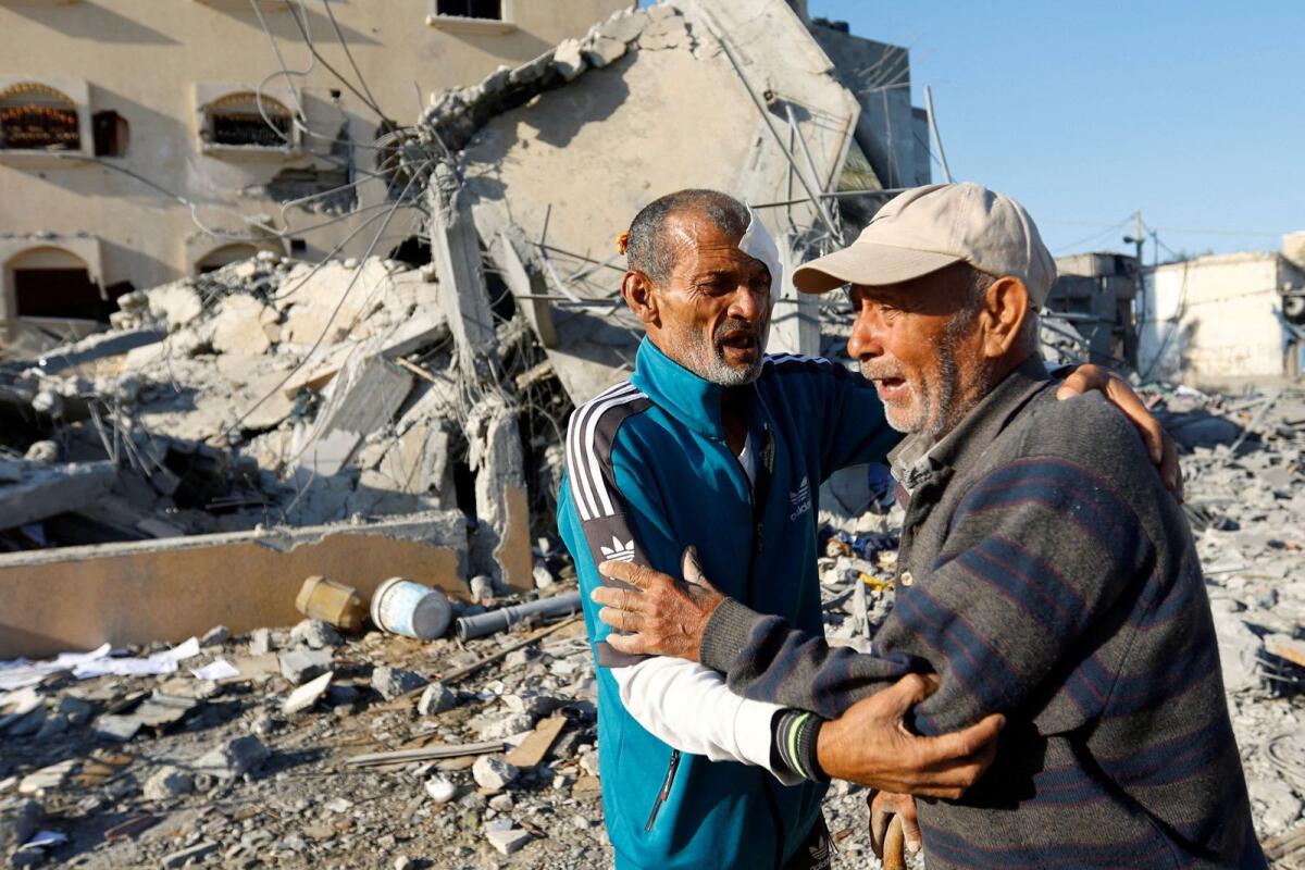 Palestinian man Mohammad Abu Daqa, who survived Israeli strikes that killed 8 family members and still searches for three others who are still trapped under the rubble of his house, reacts with a relative in front of the ruins in Khan Younis in the southern Gaza Strip Sunday. — Reuters