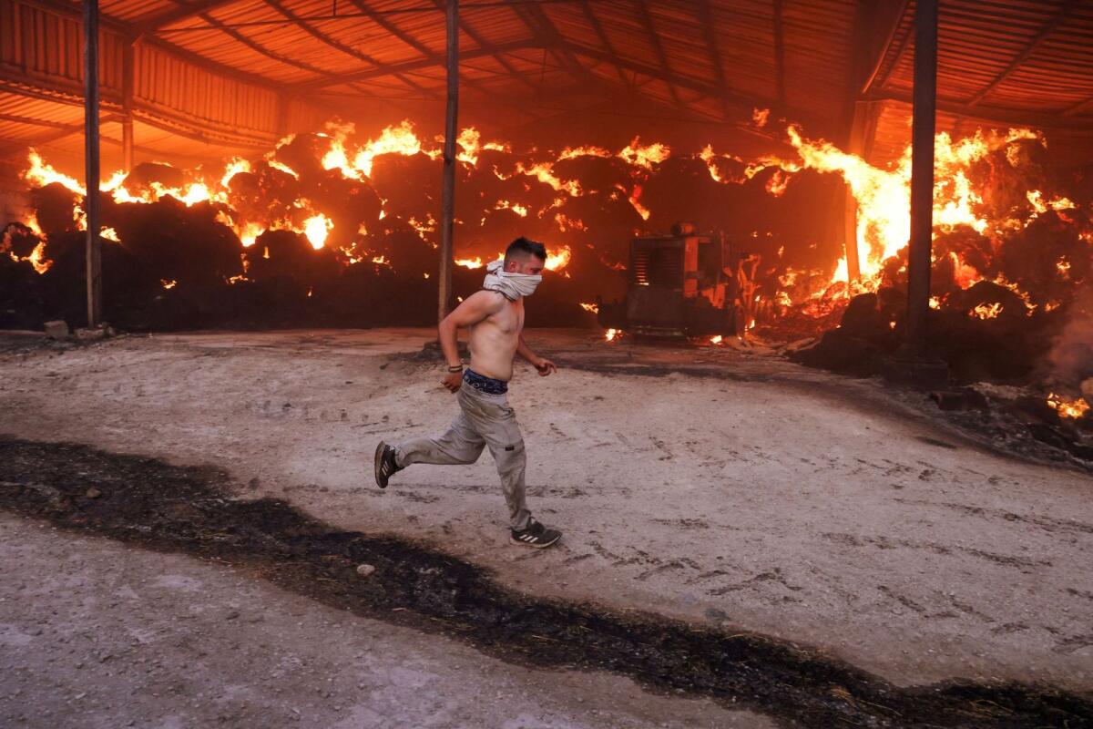 A young man runs next to a burning farm in Sesklo, in central Greece. — Reuters