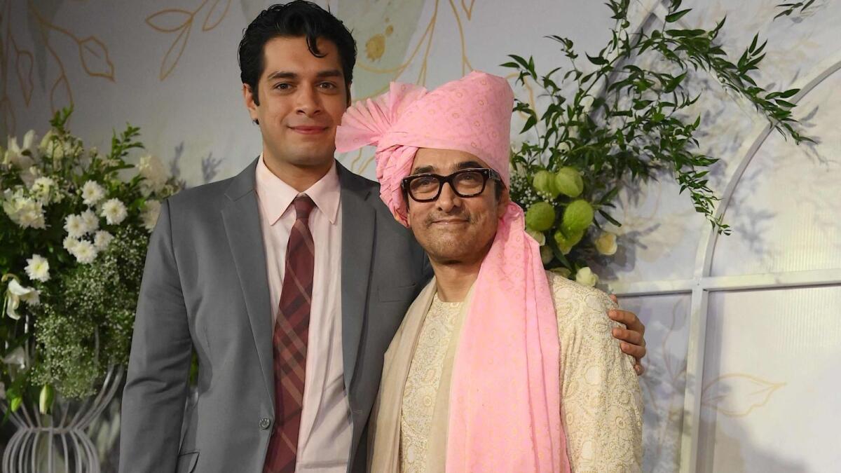 Bollywood actor Aamir Khan (R), flanked by his son Junaid Khan (L), poses for photographers as he arrives at the wedding ceremony of his daughter Ira Khan in Mumbai on January 3, 2024. (Photo by SUJIT JAISWAL / AFP)