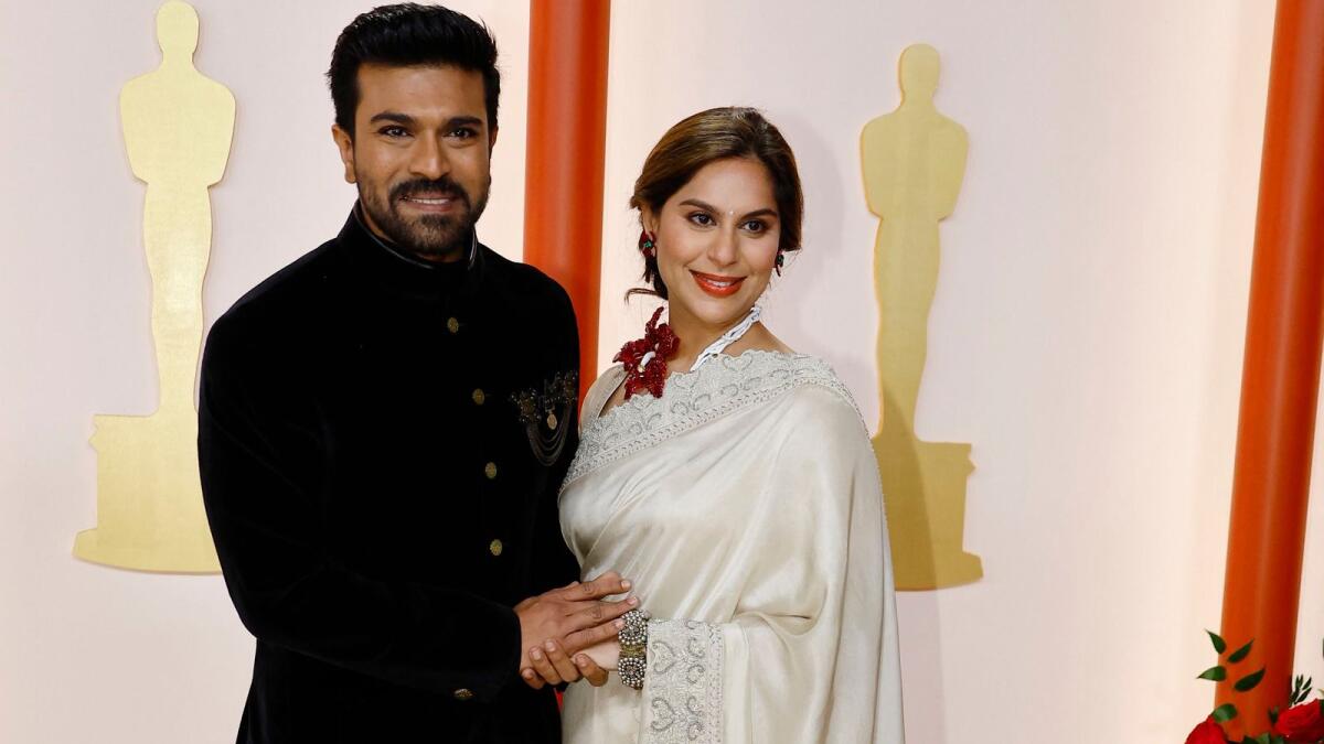 Ram Charan and wife Upasana Kamineni pose on the champagne-colored red carpet during the Oscars arrivals at the 95th Academy Awards in Hollywood, Los Angeles, California, U.S., March 12, 2023. REUTERS/Eric Gaillard