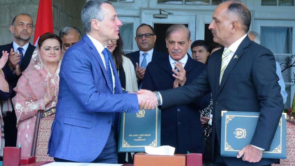 Pakistan Prime Minister Shahbaz Sharif looks on as Ignazio Cassis and Lt-Gen Inam Haider Malik shake hands after signing a Memorandum of Understanding between Pakistan and Switzerland to promote cooperation in the field of natural disasters management. — APP