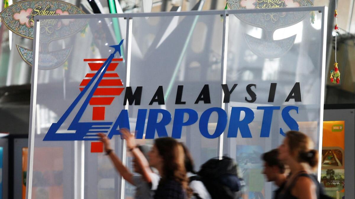 Travellers push their trolley past a logo of Malaysia Airports at the departure hall of Kuala Lumpur International Airport in Sepang, outside Kuala Lumpur. REUTERS FILE PHOTO