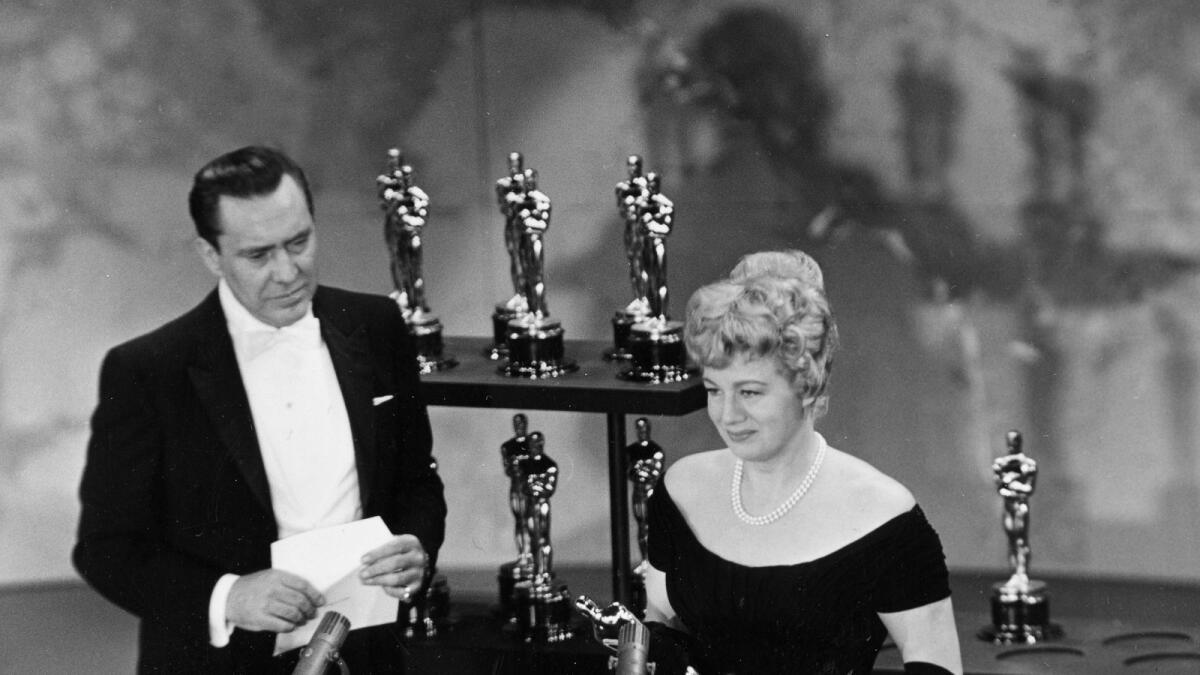 Actress Shelley Winters accepts her Oscar for best supporting actress for her role in 'The Diary of Anne Frank,' as presenter Edmond O'Brien looks on at left, during the Academy Awards in Los Angeles on April 4, 1960. At the time, actors and writers were on strike but actors and studios called a truce so all could attend the Academy Awards — a move forbidden under today’s union rules. — AP file