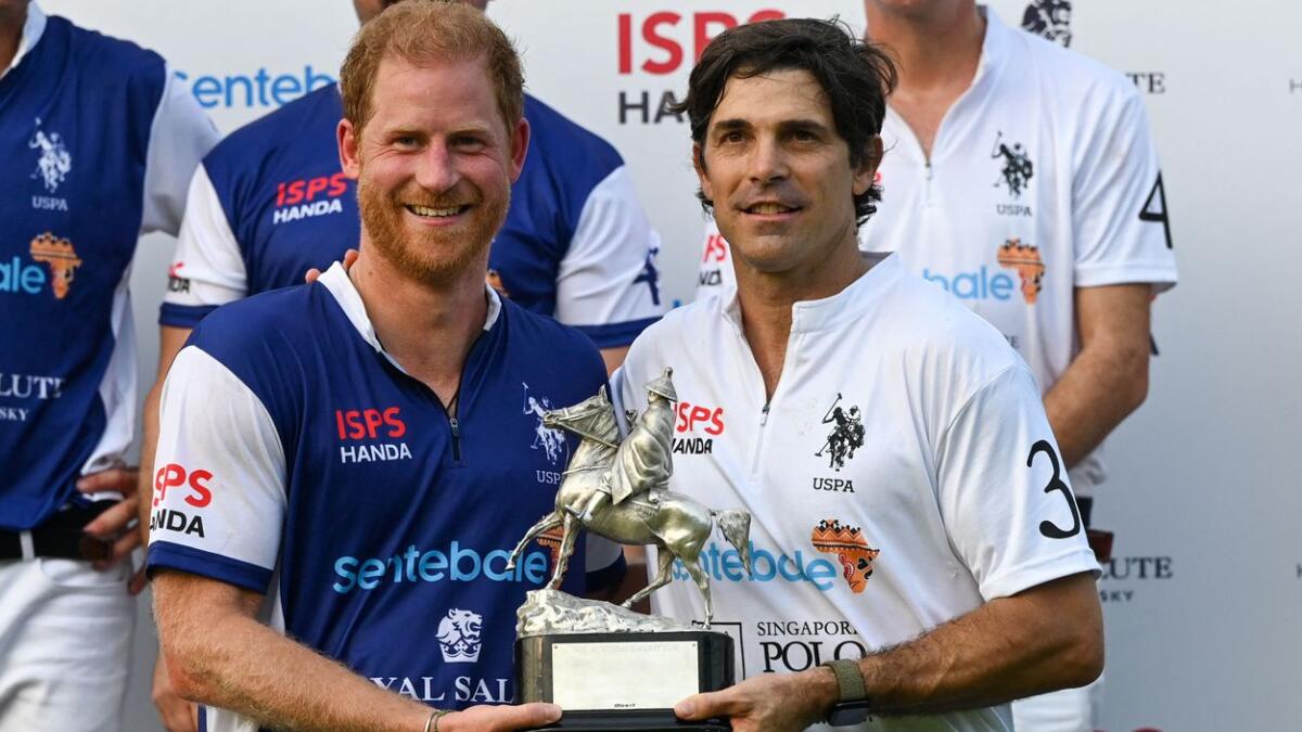 Britain's Prince Harry and Argentine polo player Nacho Figueras receive a shared trophy after the Sentebale ISPS Handa Polo Cup in Singapore on August 12. - AFP