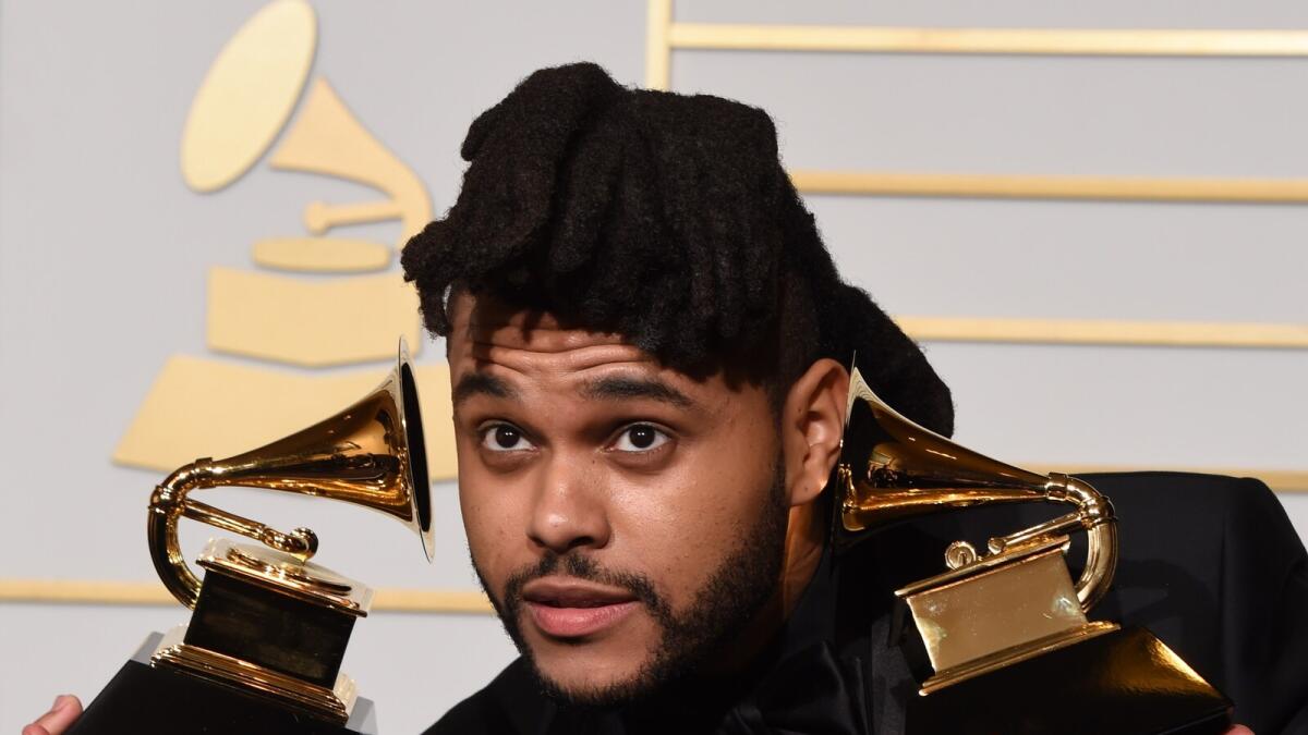 The Weeknd holds his trophies for Best R&amp;B Performance and Best Urban Contemporary Album in the press room during the 58th Annual Grammy Music Awards in Los Angeles on February 15, 2016.