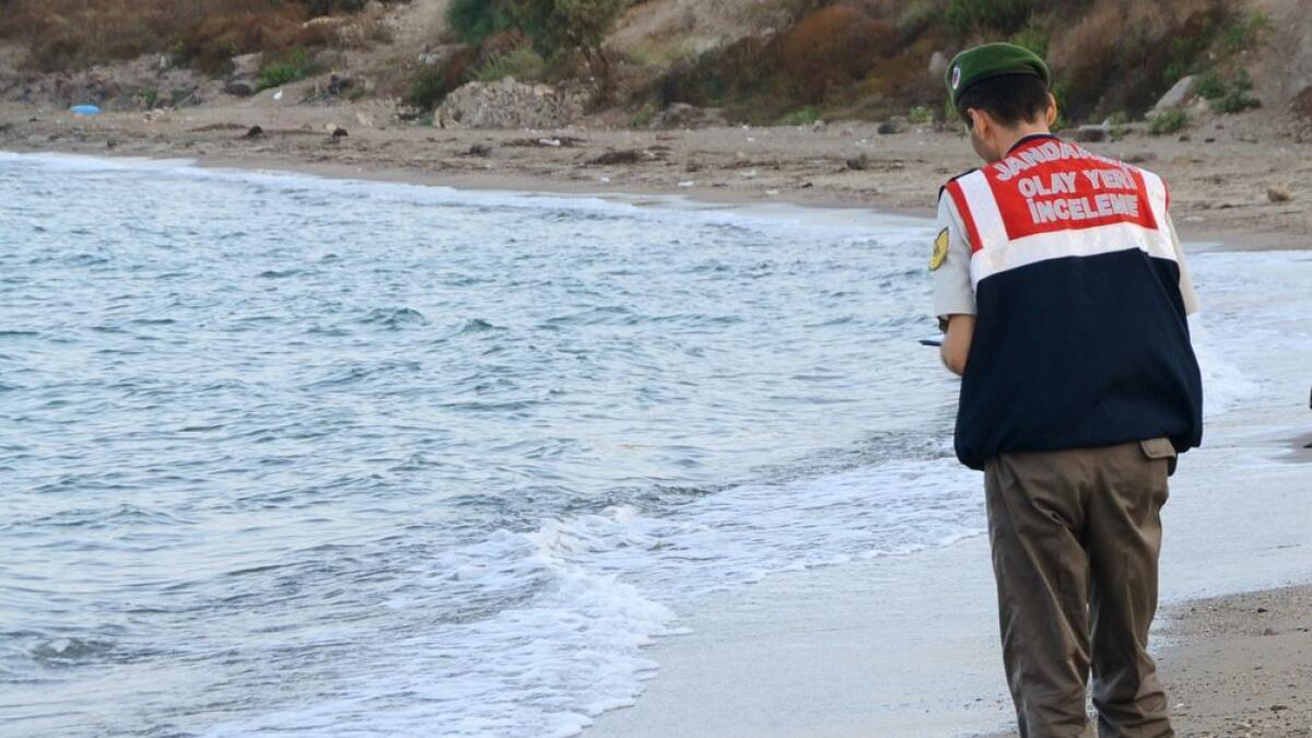 A Turkish gendarmerie stands next to a young migrant, who drowned in a failed attempt to sail to the Greek island of Kos, as he lies on the shore in the coastal town of Bodrum, Turkey.       
