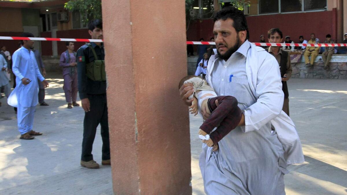 A rescue worker carries an injured child at a hospital in Jalalabad, Afghanistan