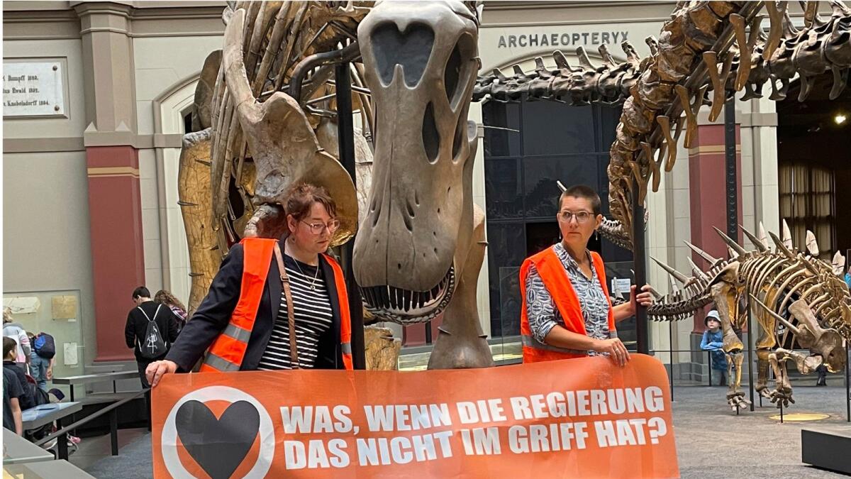 Two climate activists carrying a banner 'What if the government can't handle it?' have stuck themselves to the handrails of a dinosaur at Berlin's Museum of Natural History in Berlin, Germany, on Sunday. — AP