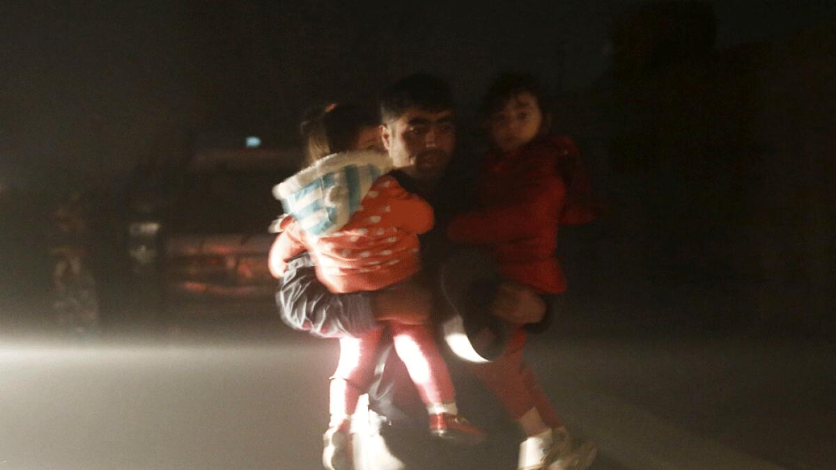 A man carries his children to a safe area from the site of an explosion in Kabul.