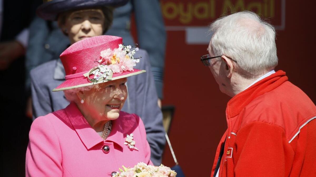 Britains Queen Elizabeth II is presented with flowers as she leaves after a visit to the Royal Mail Post Office in Windsor, England