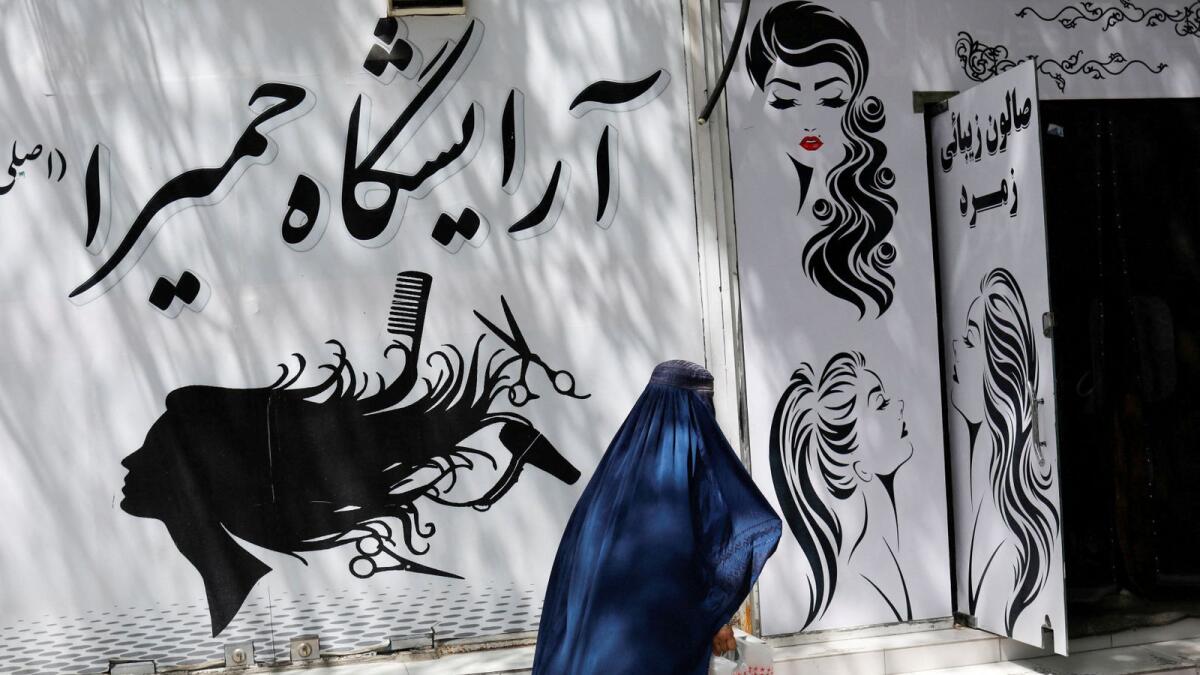 An Afghan woman walks past a beauty salon in Kabul. — Reuters file