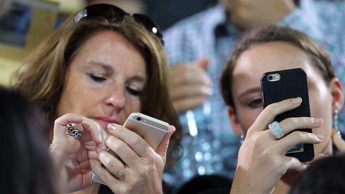 LET'S CHECK OUR PICTURES: These two women check their smartphones after taking pictures during  the match of Novak Djokovic and Tommy Robredo in the Dubai Duty Free Tennis Championships at Dubai Tennis Stadium on Monday, 22 February 2016. Photo by Kiran Prasad