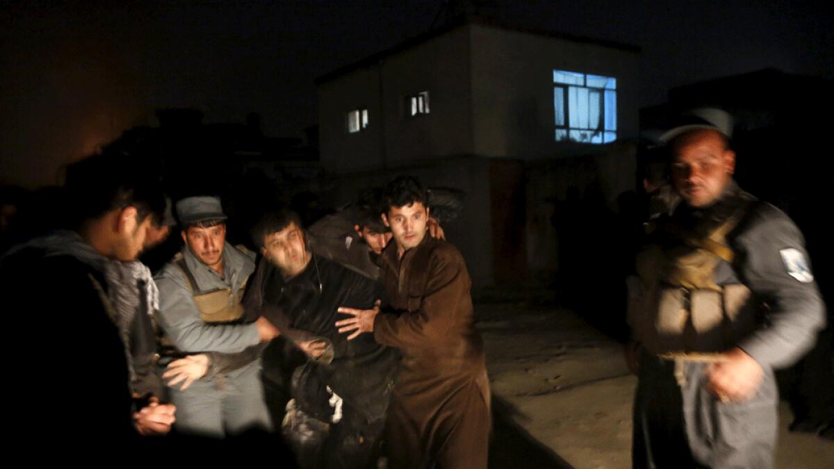 Afghan policemen carry a wounded man at the site of an explosion in Kabul.