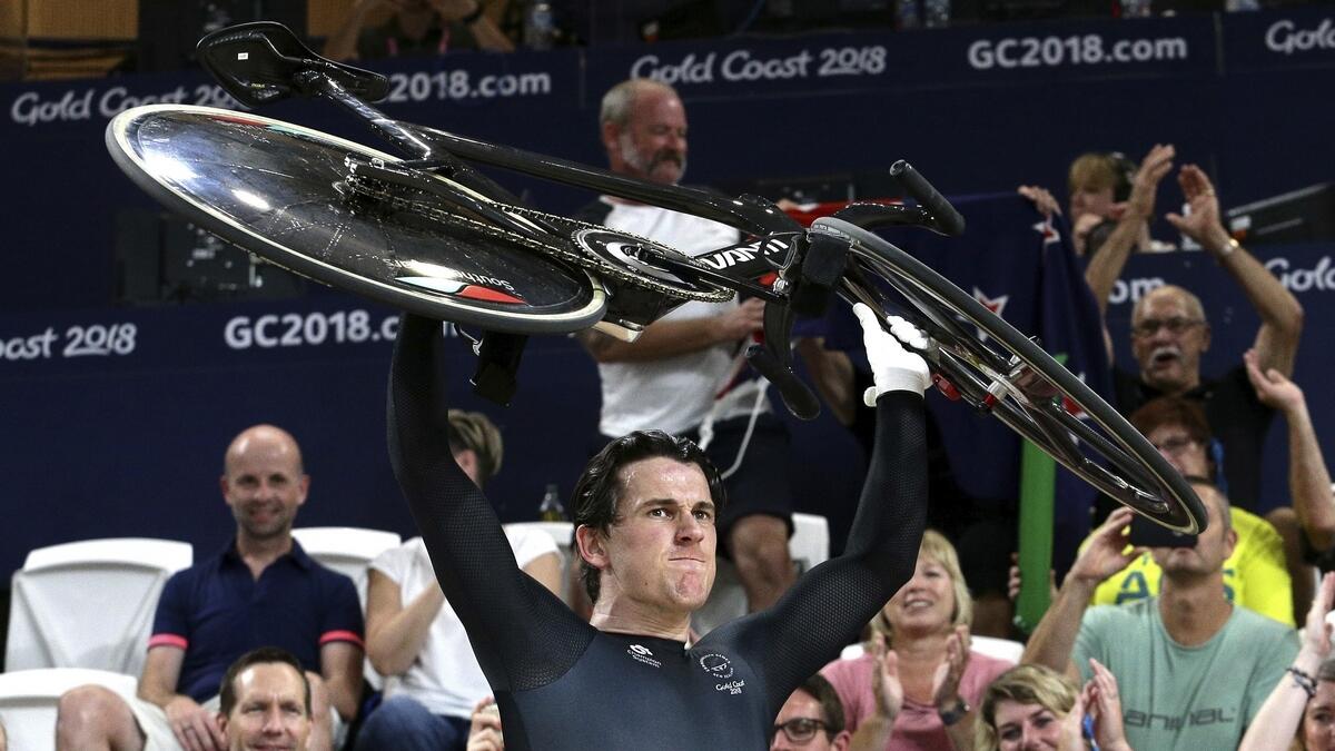New Zealand's Sam Webster lifts his bicycle after winning gold at the Men's Sprint at the Anna Meares Velodrome.
