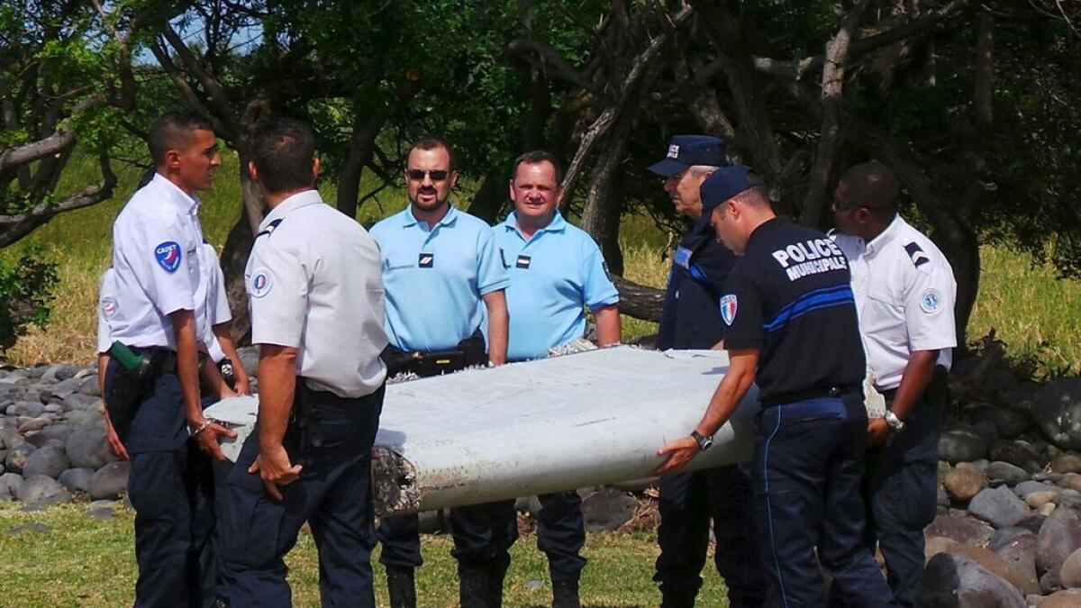 French gendarmes and police carry a large piece of plane debris which was found on the beach in Saint-Andre, on the French Indian Ocean island of La Reunion.