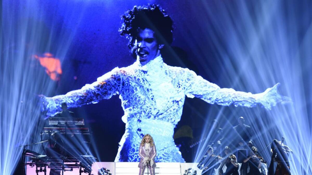Madonna performs a tribute to Prince, pictured onscreen, at the Billboard Music Awards