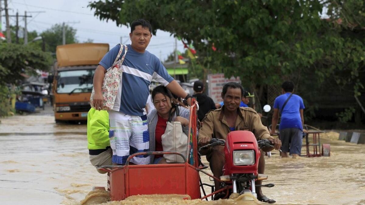  Residents ride on motorcycle taxi to cross a flooded road after heavy rain at Candaba town, Pampanga province, north of Manila.     