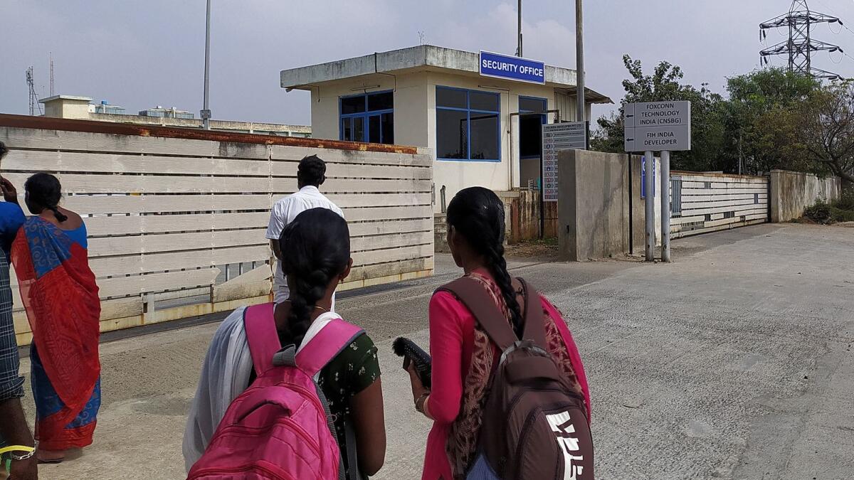 Two unidentified women wearing backpacks stand outside a security office at the main entrance to Foxconn's factory in Sriperumbudur, near Chennai, where workers assemble iPhones for Apple, on January 28, 2023. — Reuters