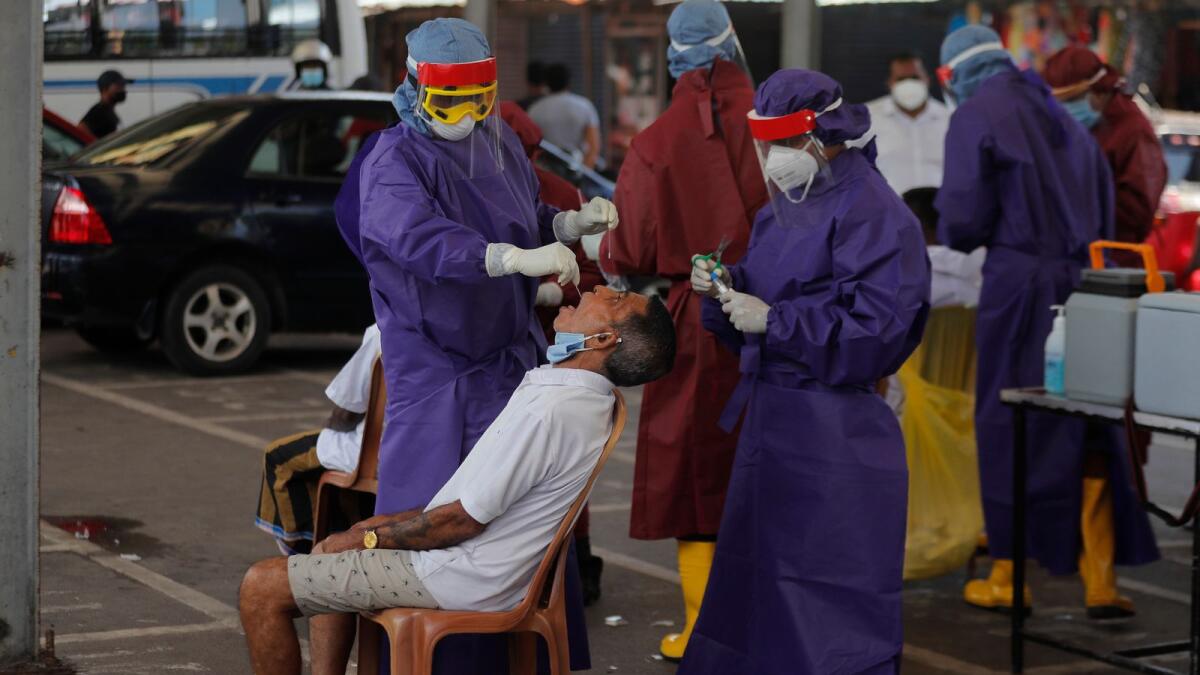 Sri Lankan health officers take a swab sample from a man to test for Covid-19 in Colombo, Sri Lanka, Thursday, Oct. 22, 2020. (AP Photo/Eranga Jayawardena)