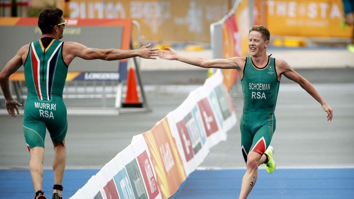 Henri Schoeman of South Africa, right, high-fives his teammate Richard Murray of South Africa as Schoeman runs to the finish line to win the mens triathlon at Southport Broadwater Parklands in the 2018 Commonwealth Games