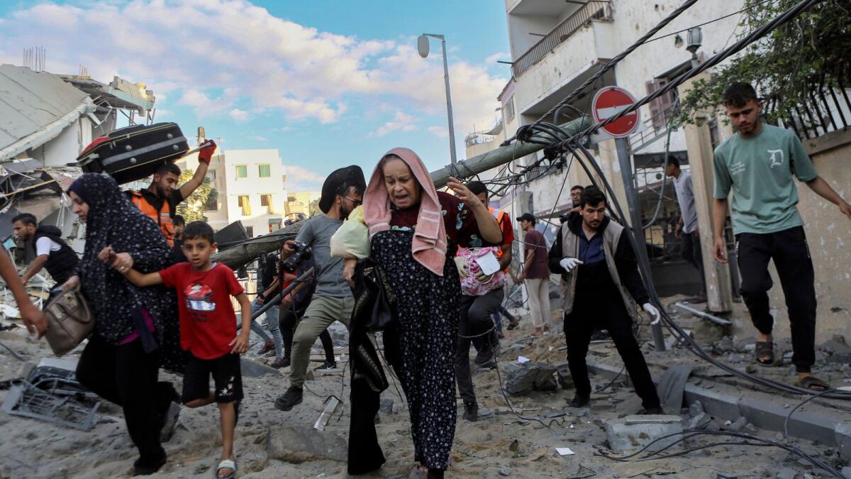 Palestinian families rush out of their homes after Israeli airstrikes in their neighborhood in Gaza City. — AP