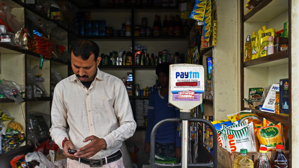 A man using a mobile device next to a sign for the PayTM online payment method at a grocery store in Delhi. KT file