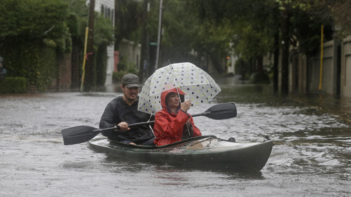 Paul Banker paddles a kayak as his wife Wink Banker takes photos on a flooded street in Charleston. — APS.C., Saturday, Oct. 3, 2015.  A flash flood warning was in effect in parts of South Carolina, where authorities shut down the Charleston peninsula to motorists.  (AP Photo/Chuck Burton) — AFP