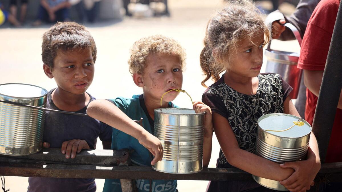 Children wait for food being distributed at a camp in Khan Yunis on Tuesday. Photo: AFP