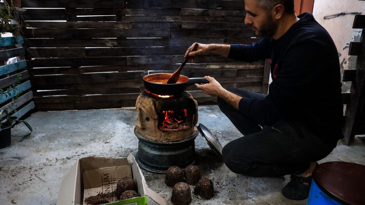 A Palestinian man manufactures a mixture of crushed olive pits to be used as fire starter amid fuel shortages in Rafah, in the southern Gaza Strip, on November 14, 2023.  AFP