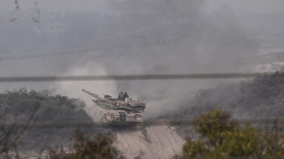 A picture taken from near the southern Israeli city of Sderot shows an Israeli Merkava tank rolling close to the Israeli border with the northern Gaza Strip on Saturday. — AFP