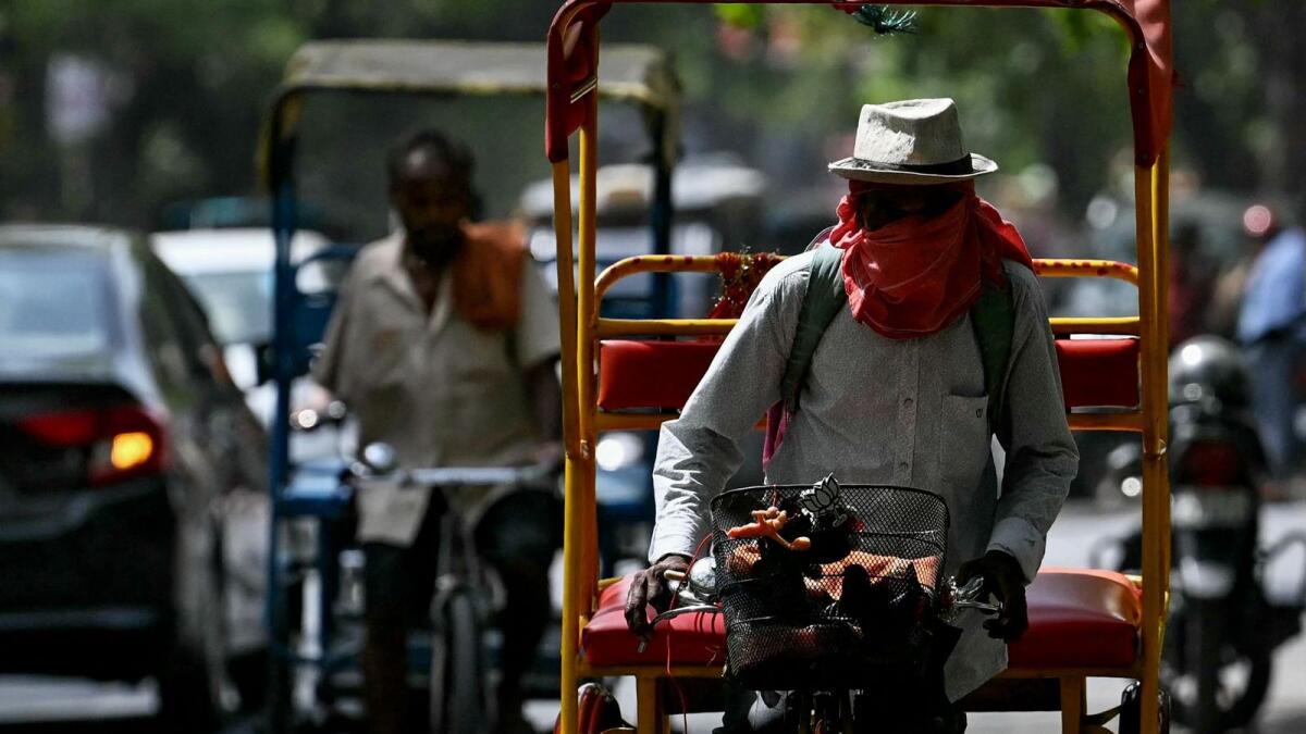 A rickshaw puller covers his face with cloth on a hot summer afternoon in New Delhi amid ongoing heatwave. AFP