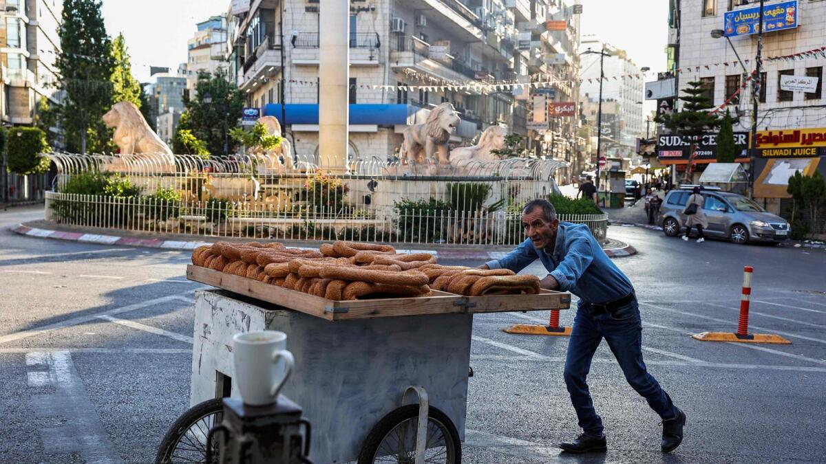 A street vendor pushes his cart at a roundabout as shops remain shuttered during a general strike in Ramallah on June 11, 2024. — AFP