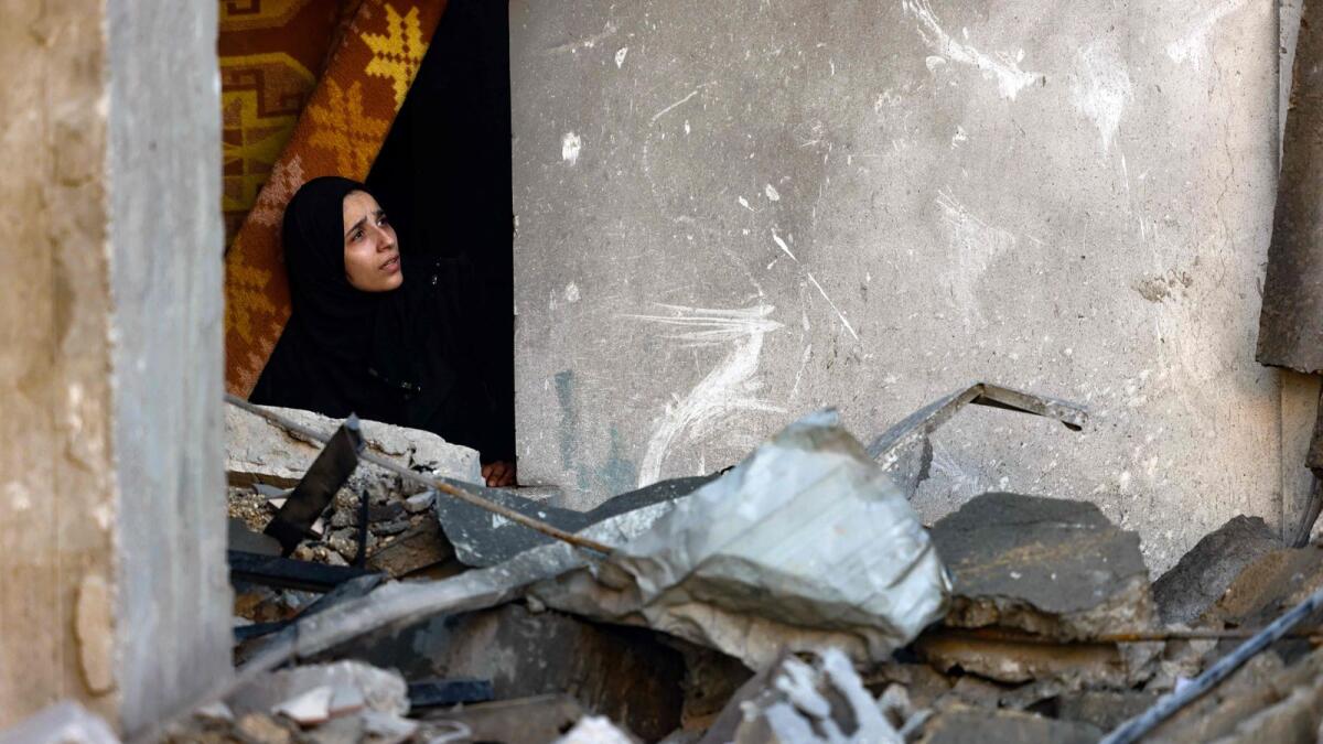 A woman looks out from the window of a damaged house following Israeli bombardment in Rafah in the southern Gaza Strip on Saturday. Photo: AFP