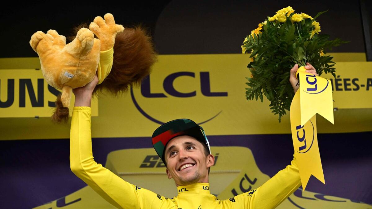 Australian rider Jai Hindley wearing the overall leader's yellow jersey celebrates on the podium after winning the 5th stage of the 110th edition of the Tour de France. - AFP