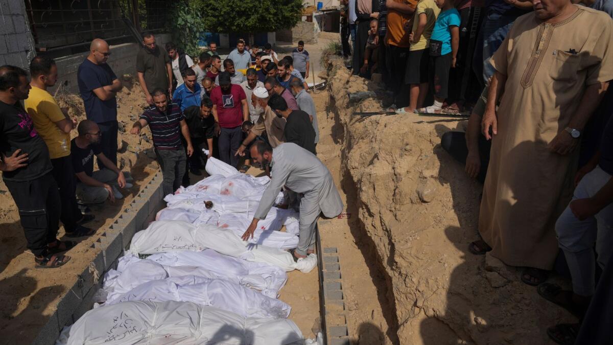 Palestinians bury the bodies of their relatives, killed in the Israeli bombardment of the Gaza Strip, Monday, Oct. 23, 2023, at a cemetery in Deir Al-Balah, Gaza. AP