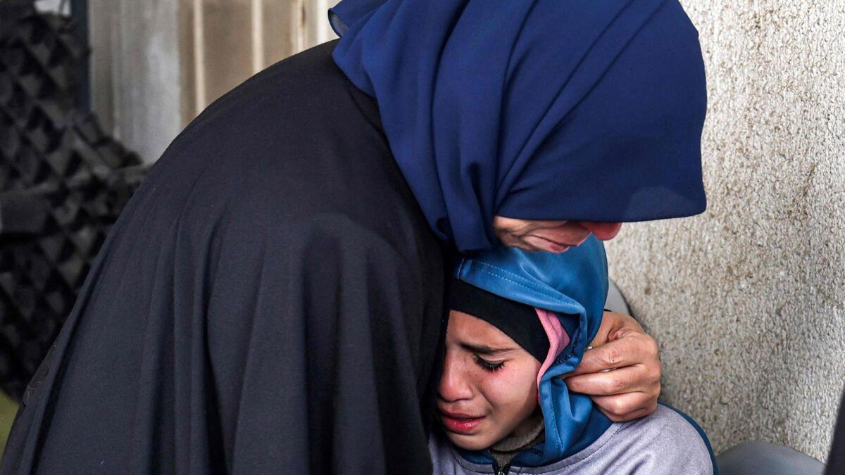 A woman embraces a crying child as they mourn relatives who were killed during Israeli bombardment at al-Najar Hospital in Rafah on March 19. Photo: AFP file