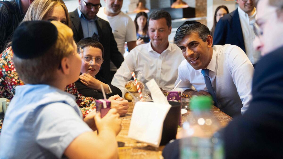 Britain's Prime Minister and Conservative Party Leader Rishi Sunak speaks with locals during a visit to a bakery during a general election campaign event in Golders Green, north London, on Sunday. — AFP