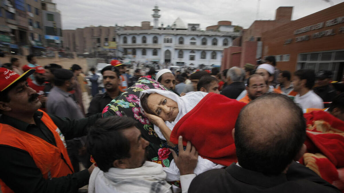 People rush a woman injured in the earthquake to a local hospital in Peshawar.