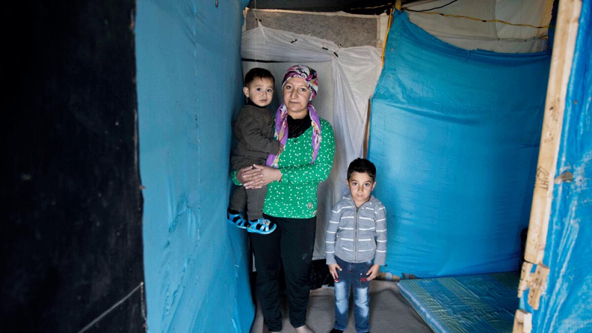 Syrian refugee Yasra Mohammad poses for a photograph with her children, at an informal tented settlement, in Irbil.