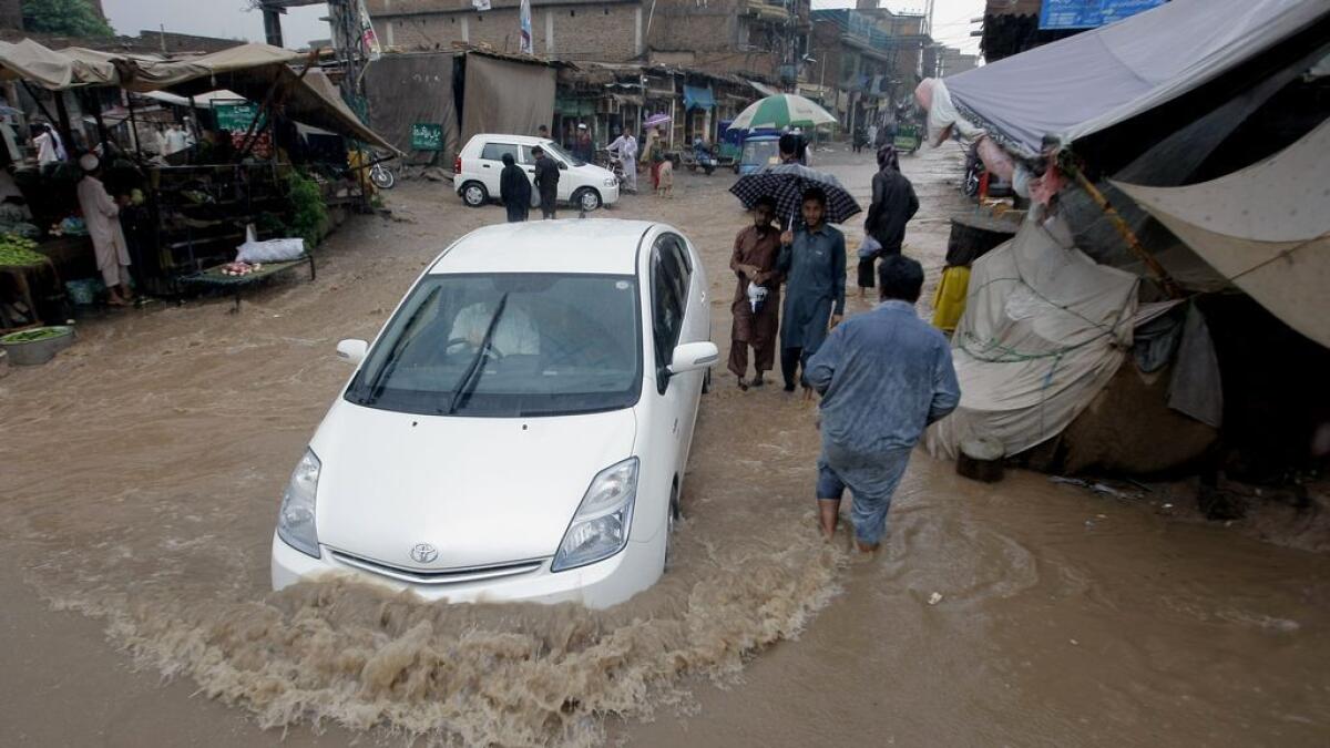 A car drives through a flooded street after heavy rains in a suburb of Peshawar, Pakistan. 