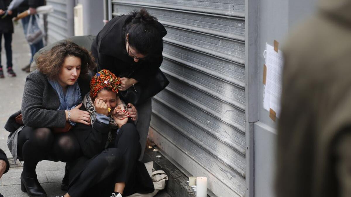 A woman is comforted by others outside the Carillon cafe and the Petit Cambodge restaurant in Paris. 