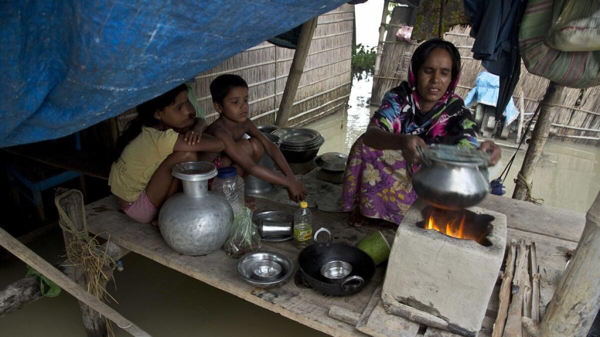 A woman prepares a meal in her flooded house at Sildubi village, in Assam. 