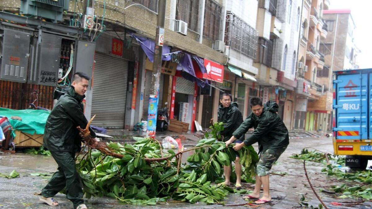 People try to remove a bough from a street as Typhoon Mujigae hits Maoming, Guangdong province
