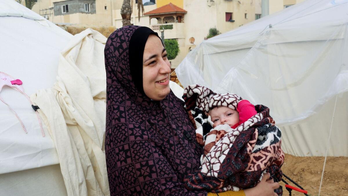 Palestinian mother Yasmine Saleh holds her baby daughter Toleen outside their tent in Rafah. - Reuters