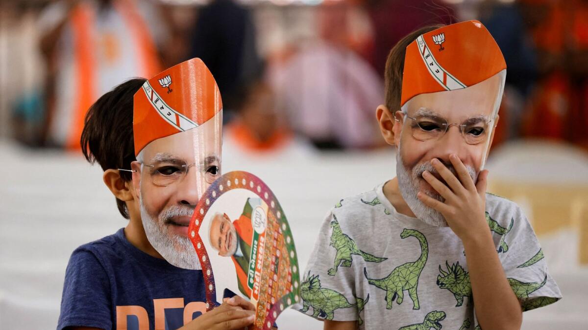 Children wearing masks of Narendra Modi attend an election campaign rally in Anand. — Reuters