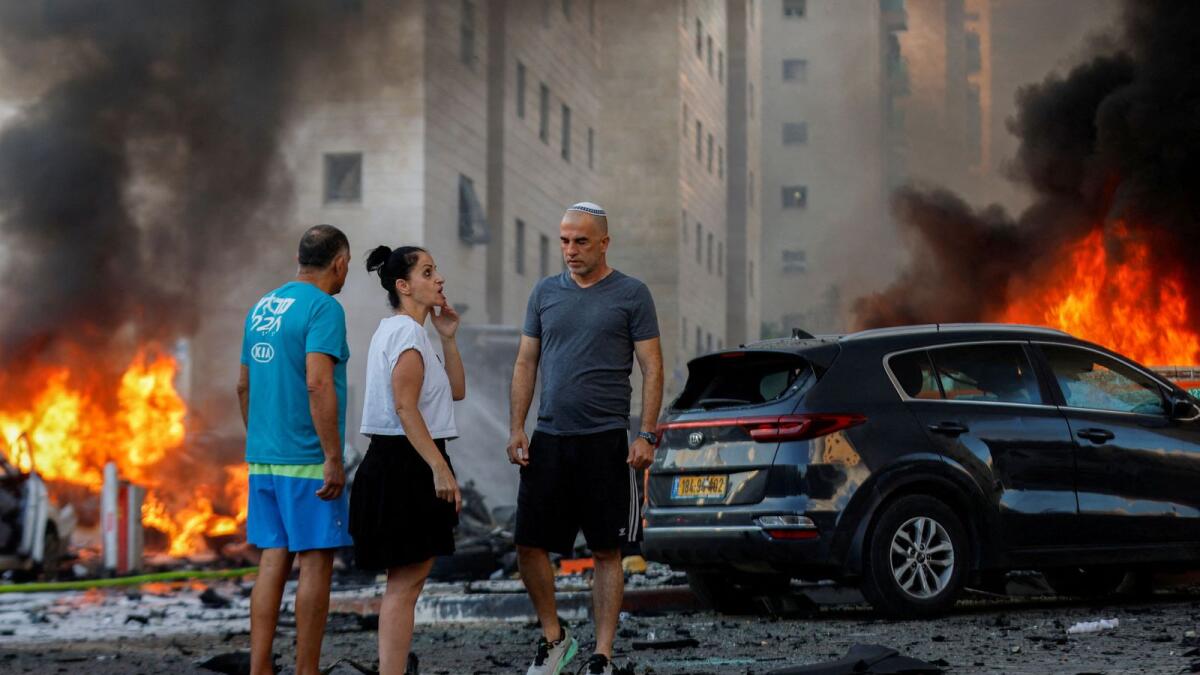 People react near a fire after rockets were launched from the Gaza Strip, in Ashkelon, Israel October 7, 2023. Reuters