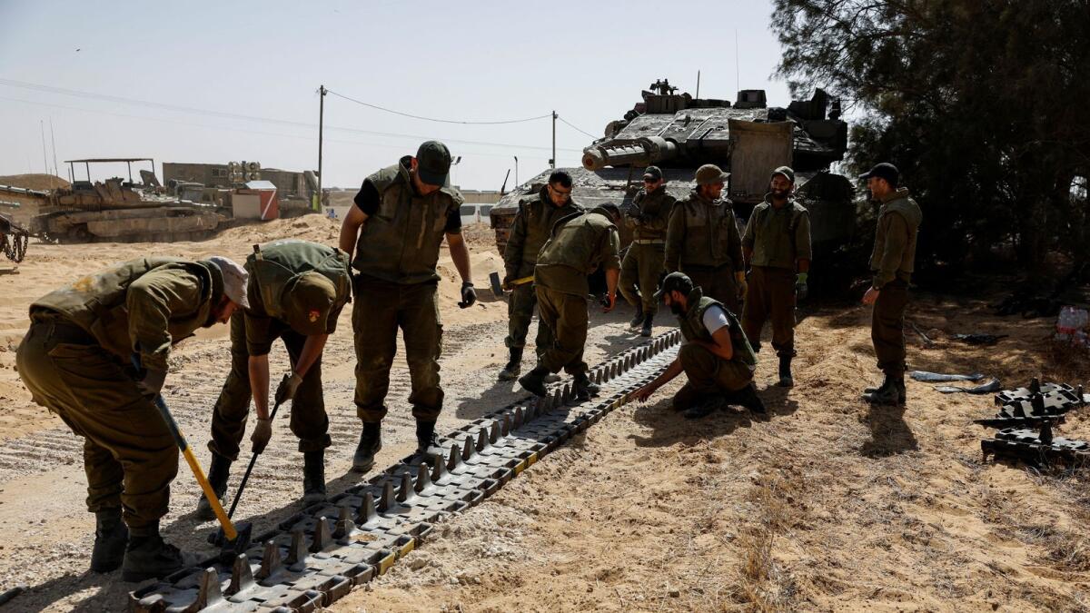 Israeli soldiers work near a military vehicle near the Israel-Gaza border, in southern Israel. — Reuters