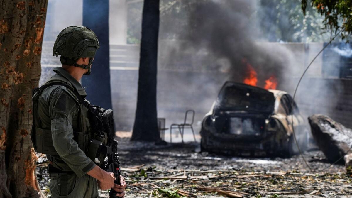A soldier looks at a burning car at the site of a rocket that was fired towards Israel from Lebanon in Kiryat Shmona. — Reuters