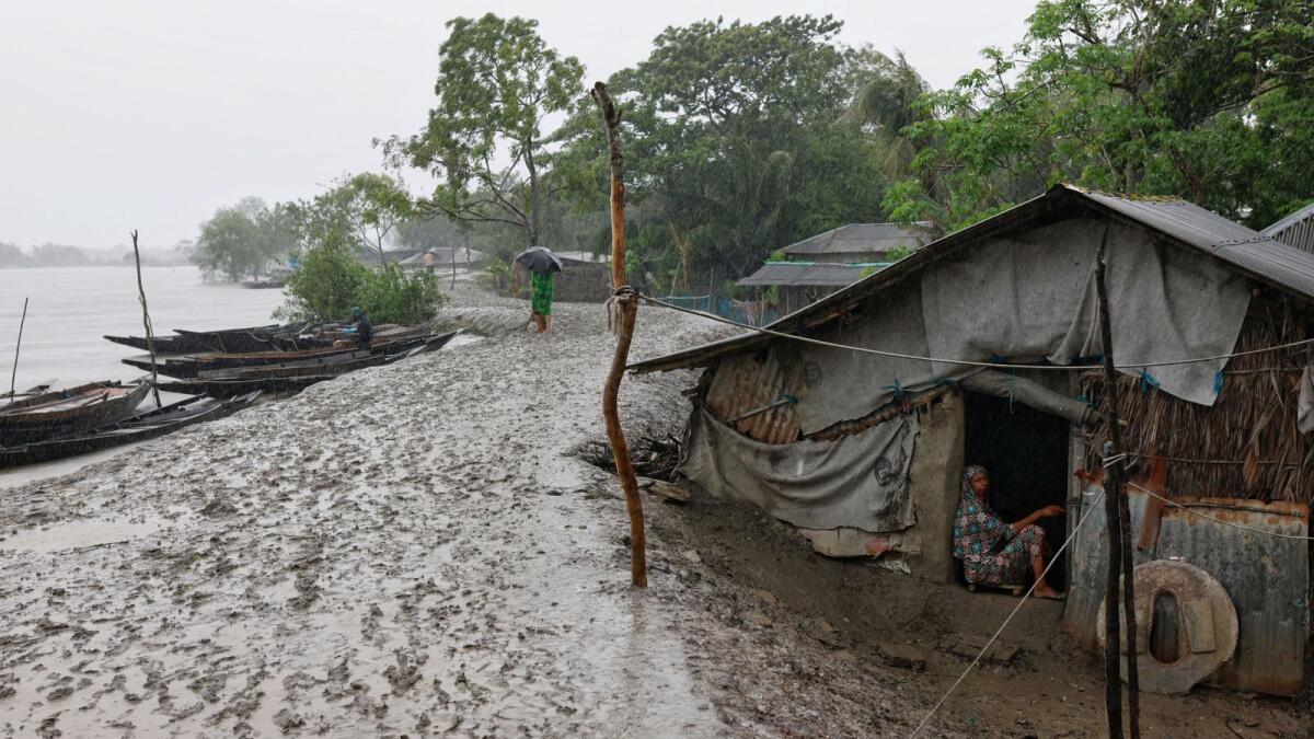 A woman, who has not moved to the cyclone shelter yet, sits in her house beside a water dam in the Shyamnagar area of Satkhira. — Photo: Reuters